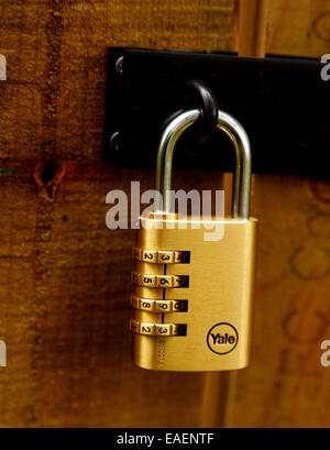 Brass and chrome combination lock made by Yale - on a wooden gate in  Cuckfield Park, West Sussex Stock Photo