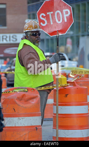 Construction worker holding a stop sign to direct auto & pedestrian traffic in Greenwich Village, downtown, New York City Stock Photo