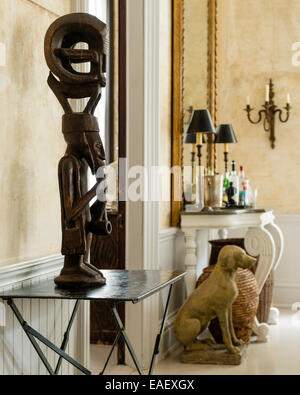 Rare African Mende carving on metal cafe table. A baroque-style painted table is used to display drinks in the background Stock Photo