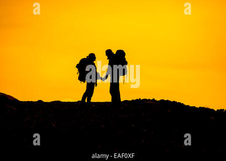 Silhouette of backpacker couple having a special moment at sunset. USA Stock Photo