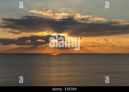 The suns sets over the calm English Channel near Burton Bradstock, on an early winter's day. Stock Photo