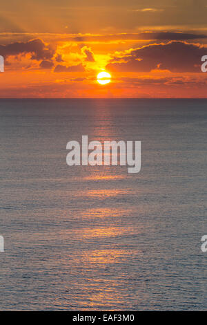 The suns sets over the calm English Channel near Burton Bradstock, on an early winter's day. Stock Photo