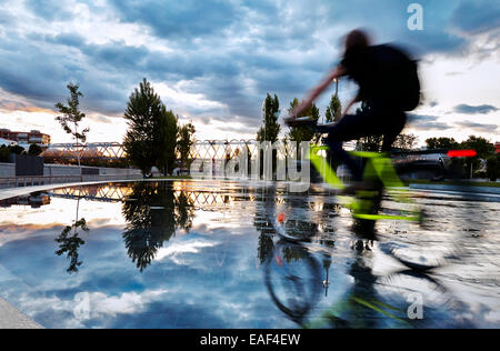 Cyclist passing by the pools and fountains in Madrid Rio Park. Madrid. Spain Stock Photo