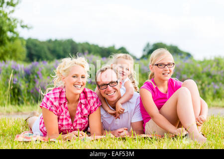 Family of Parents and daughters sitting on grass of lawn or field Stock Photo