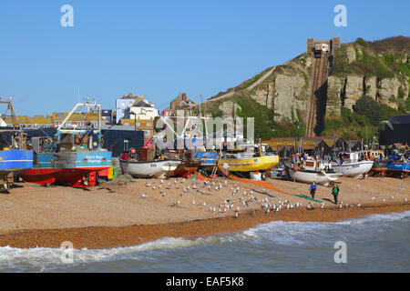 Couple walking on Hastings Old Town Stade beach, in front of the fishing boats and the Hastings Contemporary Art Gallery, East Sussex, UK. Stock Photo