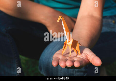 Origami orange color giraffe on hand. Stock Photo