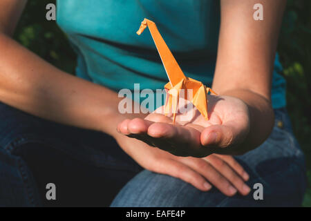 Origami orange color giraffe on hand. Stock Photo