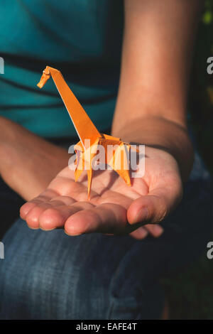 Origami orange color giraffe on hand. Stock Photo