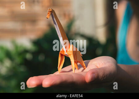 Origami orange color giraffe on hand. Stock Photo