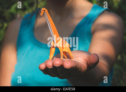 Origami orange color giraffe on hand. Stock Photo