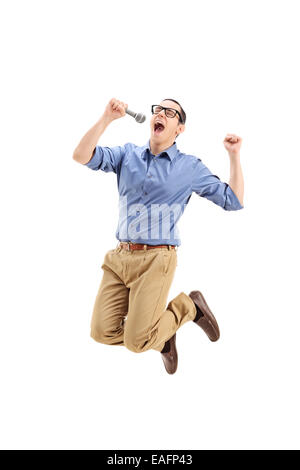 Excited guy singing on a microphone and jumping out of joy isolated on white background Stock Photo