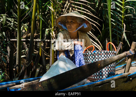 Vietnamese elderly woman seated in a traditional boat on Mekong River Stock Photo