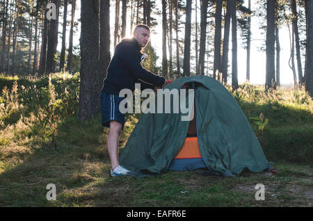 Man fix tent in the forest. Sunshine Stock Photo