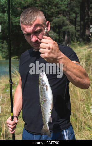 Fisherman caught a fish in mountain dam Stock Photo