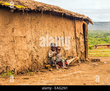 Two african boys sitting in front of a Masai tribe village house Stock Photo