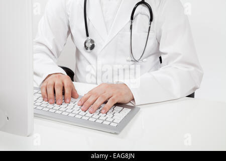 doctor typing on computer in doctor's office Stock Photo