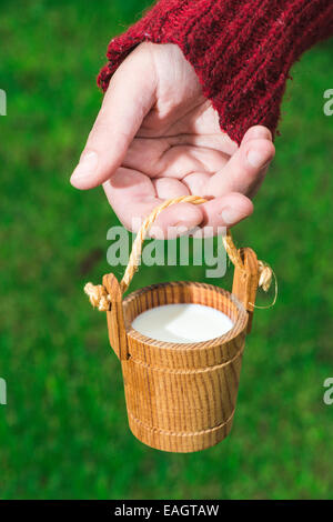 Women hold small wooden mug of milk Stock Photo