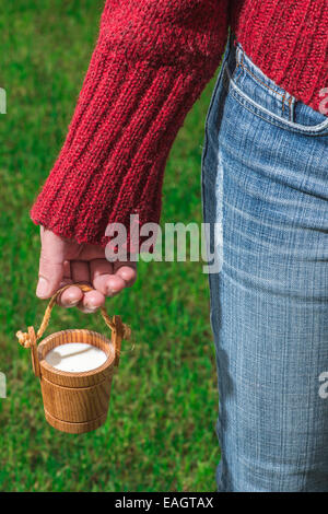 Women hold small wooden mug of milk Stock Photo