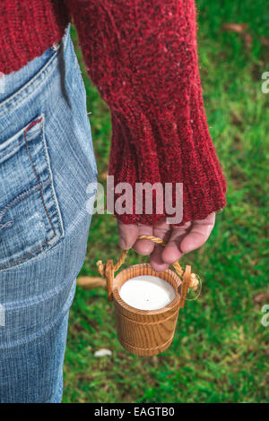 Women hold small wooden mug of milk Stock Photo