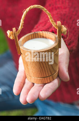 Women hold small wooden mug of milk Stock Photo