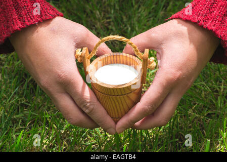 Women hold small wooden mug of milk Stock Photo