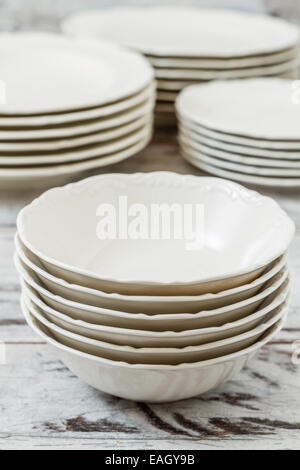 Pile of white porcelain plates lined on white wooden background
