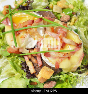 Salad with hot goat cheese, ham and vegetables on outdoors table Stock Photo