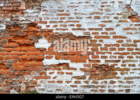 Wall built of red bricks with white painting partially destroyed Stock Photo