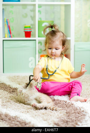 little kid girl plays doctor with kitten Stock Photo