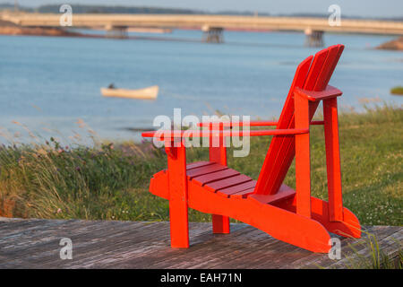 A red lawn chair with a view of a seaside vista in rural Prince Edward Island, Canada.