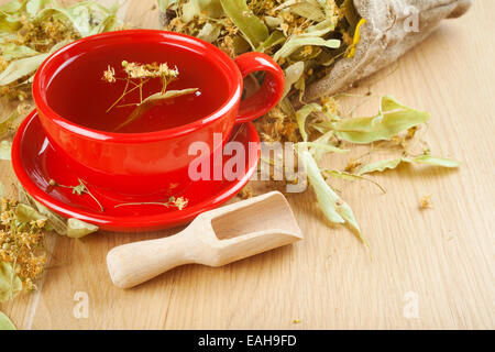 cup of linden tea and flowers in canvas bag on wooden table Stock Photo