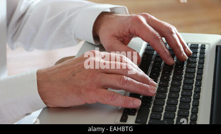 Close shot of male hands typing on a laptop keypad. Stock Photo
