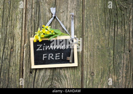 chalkboard with key, yellow flowers and german text: room for rent Stock Photo
