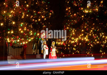 Carolers: Victorian-style Christmas Carolers are surrounded by spectacular Christmas trees lit with thousands of lights. Stock Photo