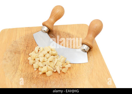 Coarsely chopped macadamia nuts with a rocking knife on a wooden chopping board, isolated on a white background Stock Photo