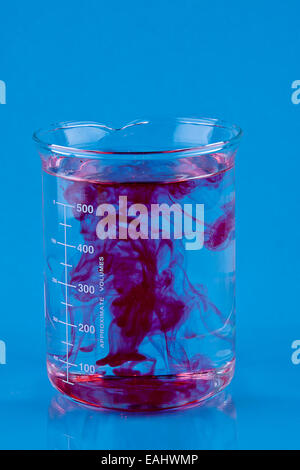 Food coloring dropped into glass of water and dispersing Stock 