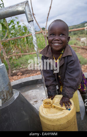 Three year-old Abigail Chemtai is the first to draw water from a newly installed well in Sukuroi village, Bukwo District, Uganda Stock Photo