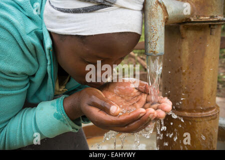 An adolescent girl drinks fresh, clean water from the newly-installed well in her village in Bukwo District, Eastern Uganda, Eas Stock Photo