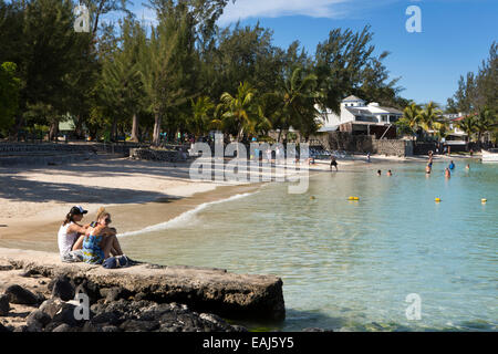 Mauritius, Pereybere, public beach, visitors sat in sunshine, on concrete jetty Stock Photo