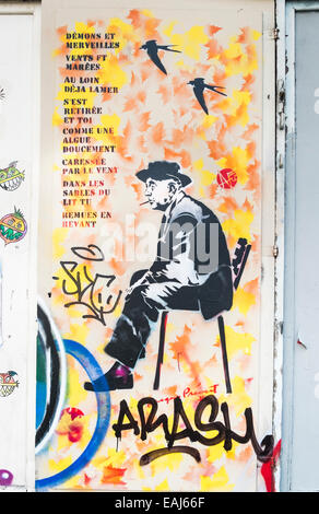 stencil graffito showing french poet jacques prévert sitting on a chair next to the lyrics of the chanson demons et merveilles Stock Photo