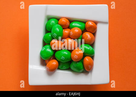 limited edition peanut M&M's for Halloween in bowl isolated on orange coloured  background - looking down on from above peanut M&Ms Stock Photo