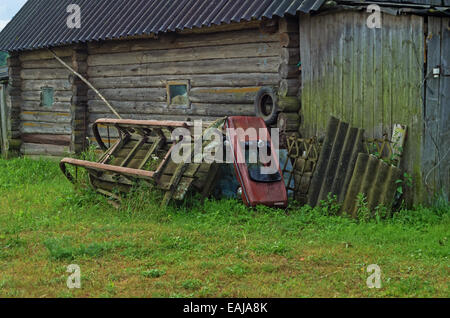 Village landscape. Wooden winter sledge and the old children's car near a barn. Stock Photo