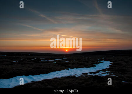 Beautiful sunset over the moors above Glossop, Derbyshire, with colour in the high clouds. Snow in the foreground. Stock Photo