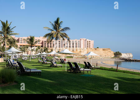 Beach chairs and green lawns along the sandy beach in a luxury resort. Muscat, Oman. Stock Photo