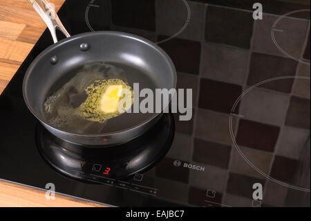 Butter melting in a frying pan, on an induction hob.Unhealthy, cholestrol. Stock Photo