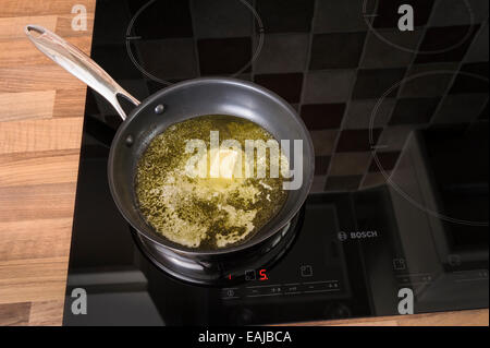 Butter melting in a frying pan, on an induction hob.Unhealthy, cholestrol. Stock Photo