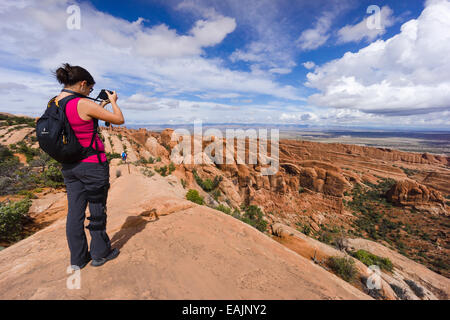 Female hiker taking a photo at Devils Garden trail. Arches National Park, Moab, Utah, USA. Stock Photo
