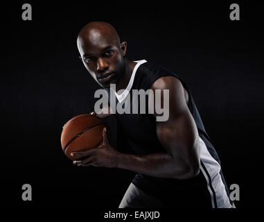 Portrait of fit young male athlete playing basketball. African American basketball player against black background Stock Photo