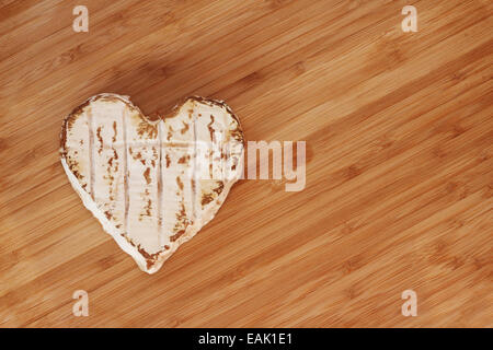 Neufchatel cheese shaped like heart on wooden cutting board Stock Photo