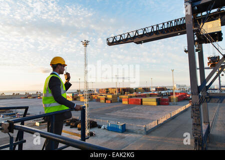 Worker using walkie-talkie near crane Stock Photo